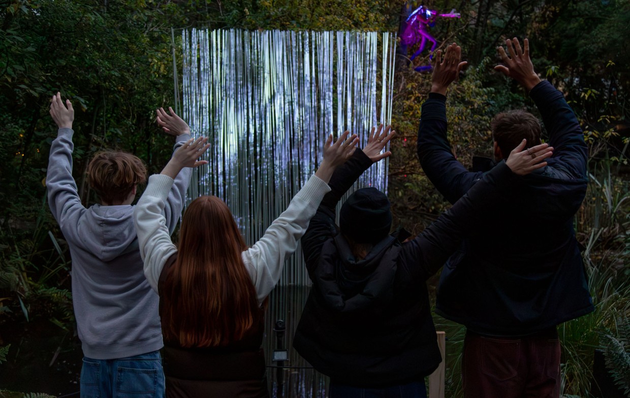 Family engaging with an interactive light sculpture in forest